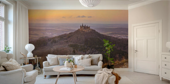 Medieval Majesty wallpaper mural of a hilltop castle at golden sunset behind a cream sofa in a bright living room