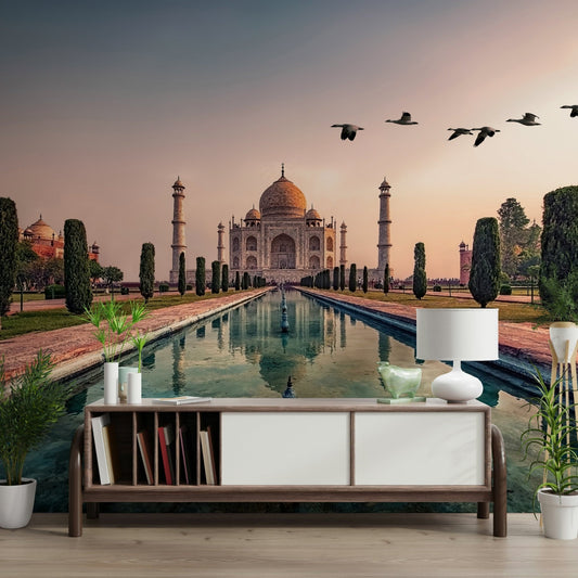 India's Taj Mahal: A Timeless Wonder wallpaper mural at sunset above a wood sideboard with a lamp and plants
