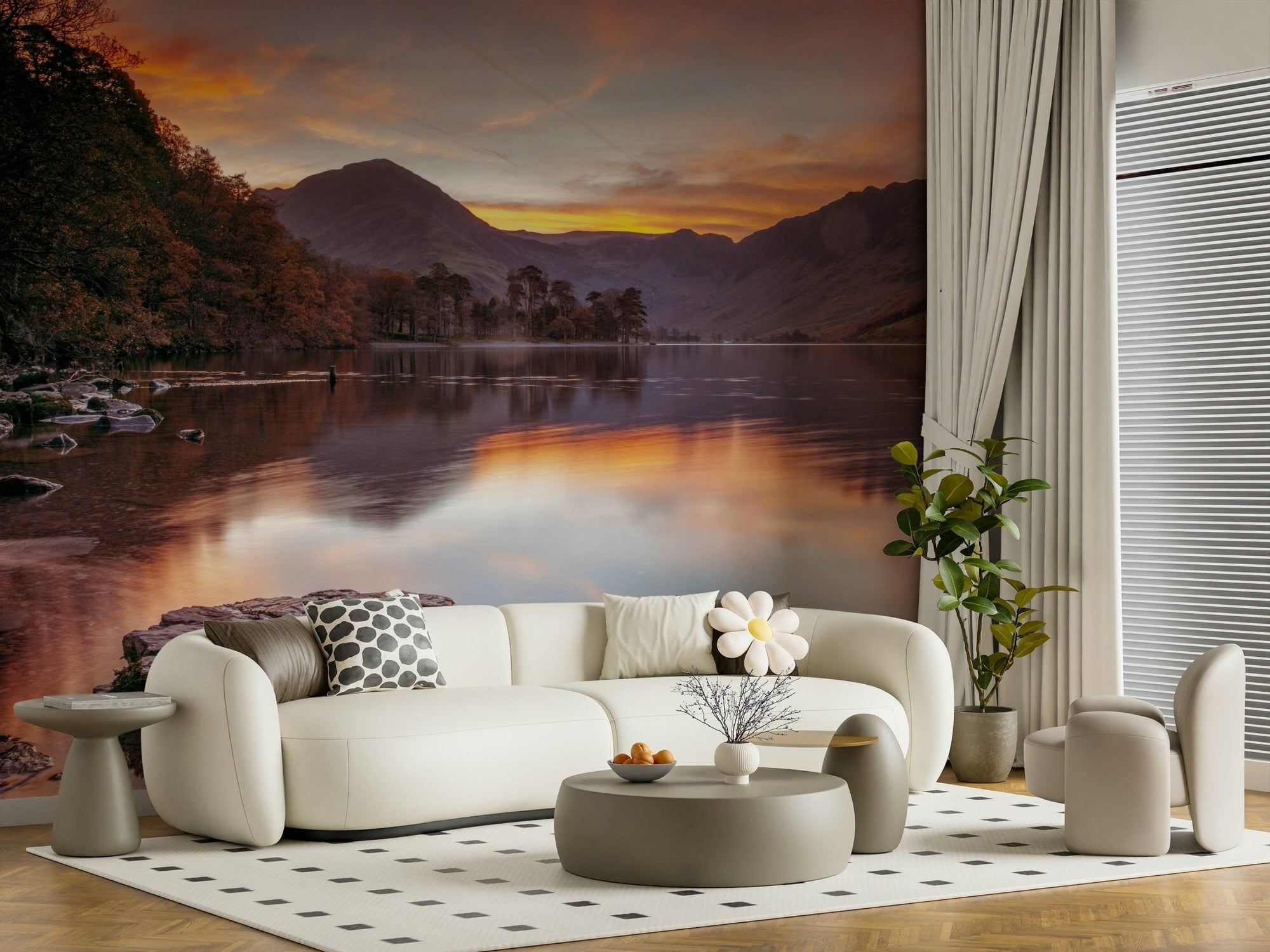 Lakeland Sunrise wallpaper mural of a mountain lake at sunrise behind a curved cream sofa and grey tables in a living room