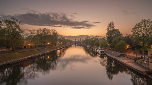 Wandmuurschildering met spiegelend kanaalwater bij zonsondergang