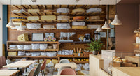 Retail-style cheese shelves wall mural for café corner, warm lighting look, feature wall use