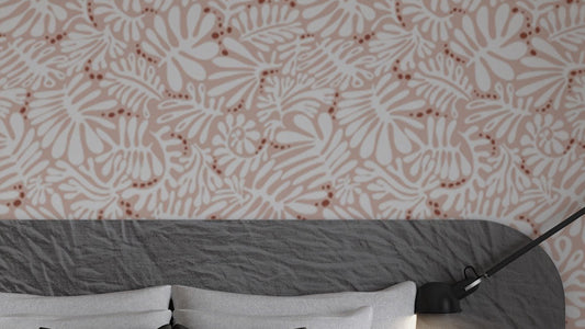 Whimsical Blush Botanical wallpaper in pink with white florals above a grey upholstered bedroom headboard