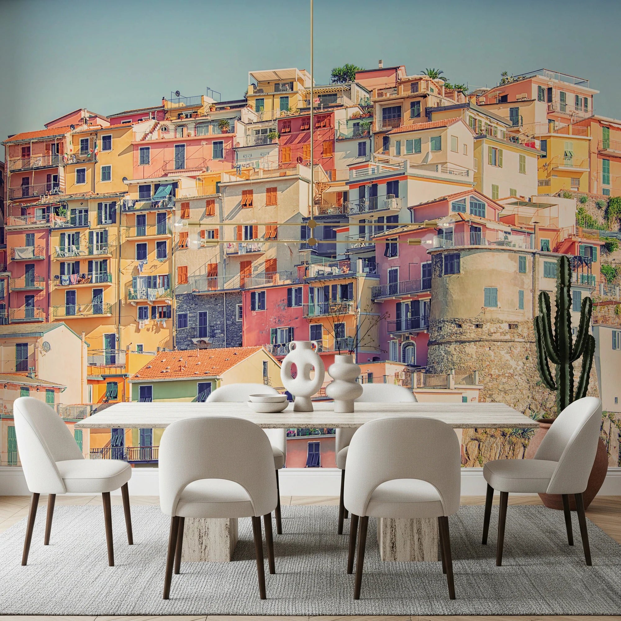 Manarola Vista wall mural of colorful Cinque Terre houses behind a white dining table and cream chairs