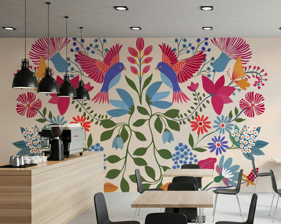Mexican Garden wallpaper mural of folk-art birds and pink flowers behind a wood coffee counter and dining tables in a cafe