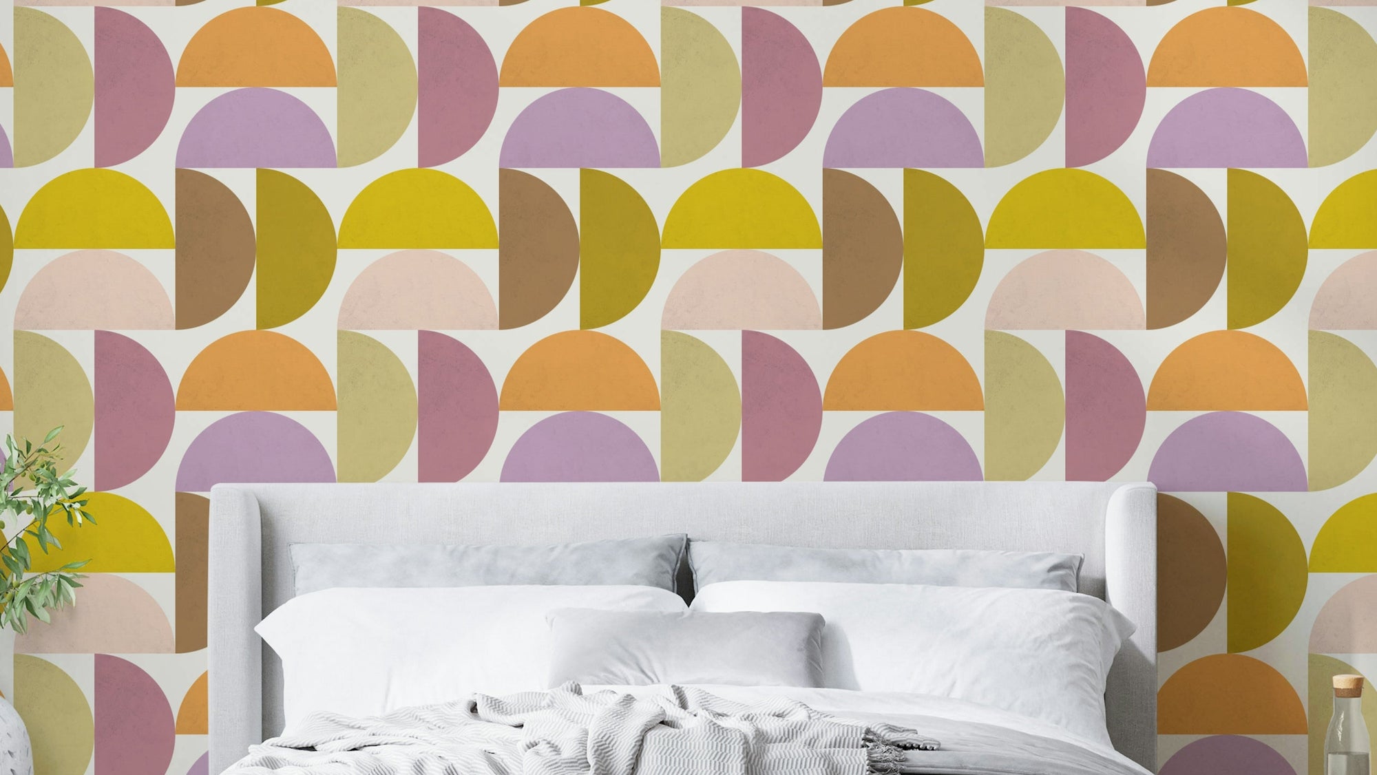 Mid-Century Modern Hues wallpaper mural in pink and yellow behind a white upholstered bed with white bedding