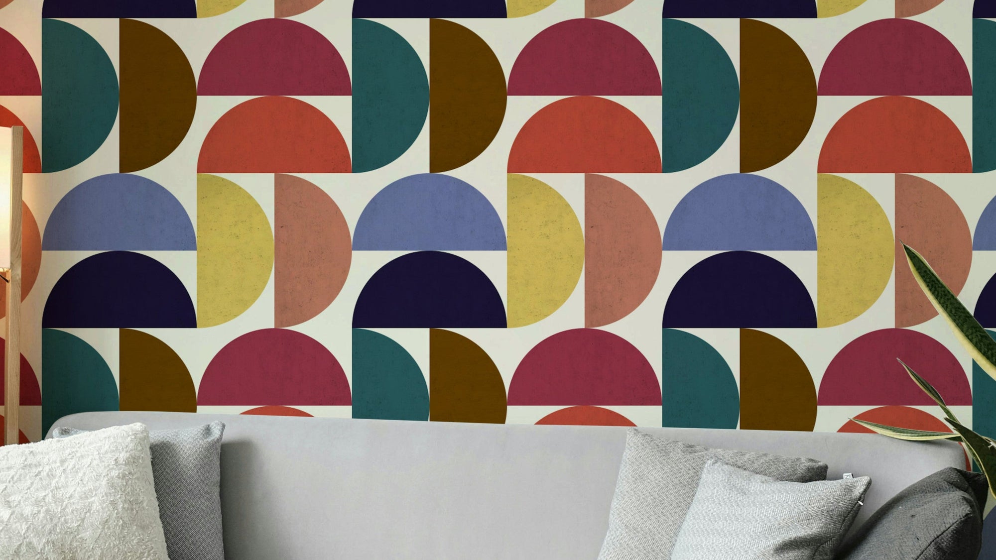 Mid-Century Modern Mosaic wallpaper mural in bold retro colors behind a grey sofa with textured pillows