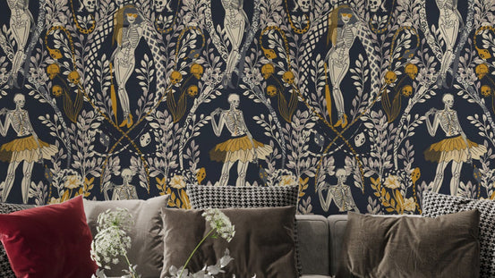 Midnight Masquerade Halloween wallpaper in navy with gold dancing skeletons above a grey sofa with cushions in a living room
