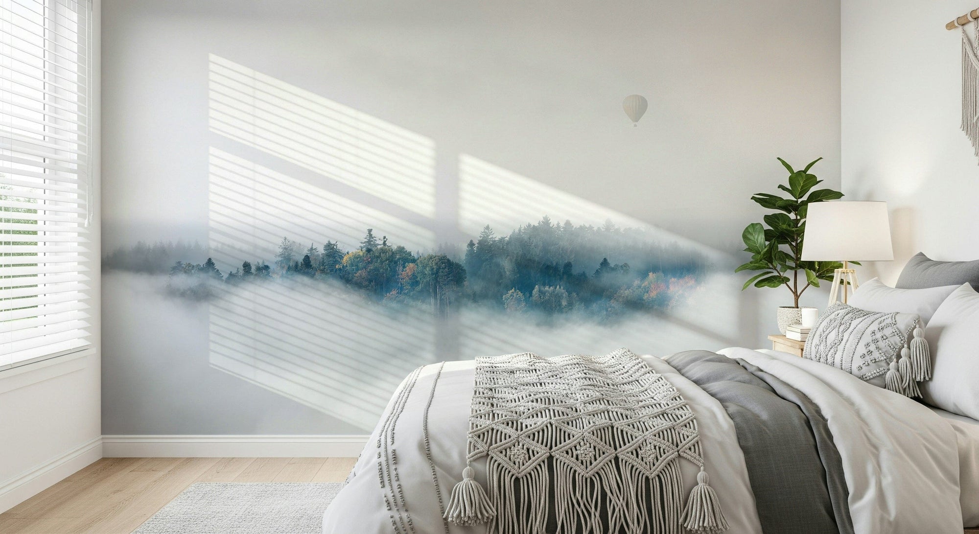 Above the Mist wallpaper mural of a foggy forest and balloon behind a white bed with a macrame throw in a bedroom