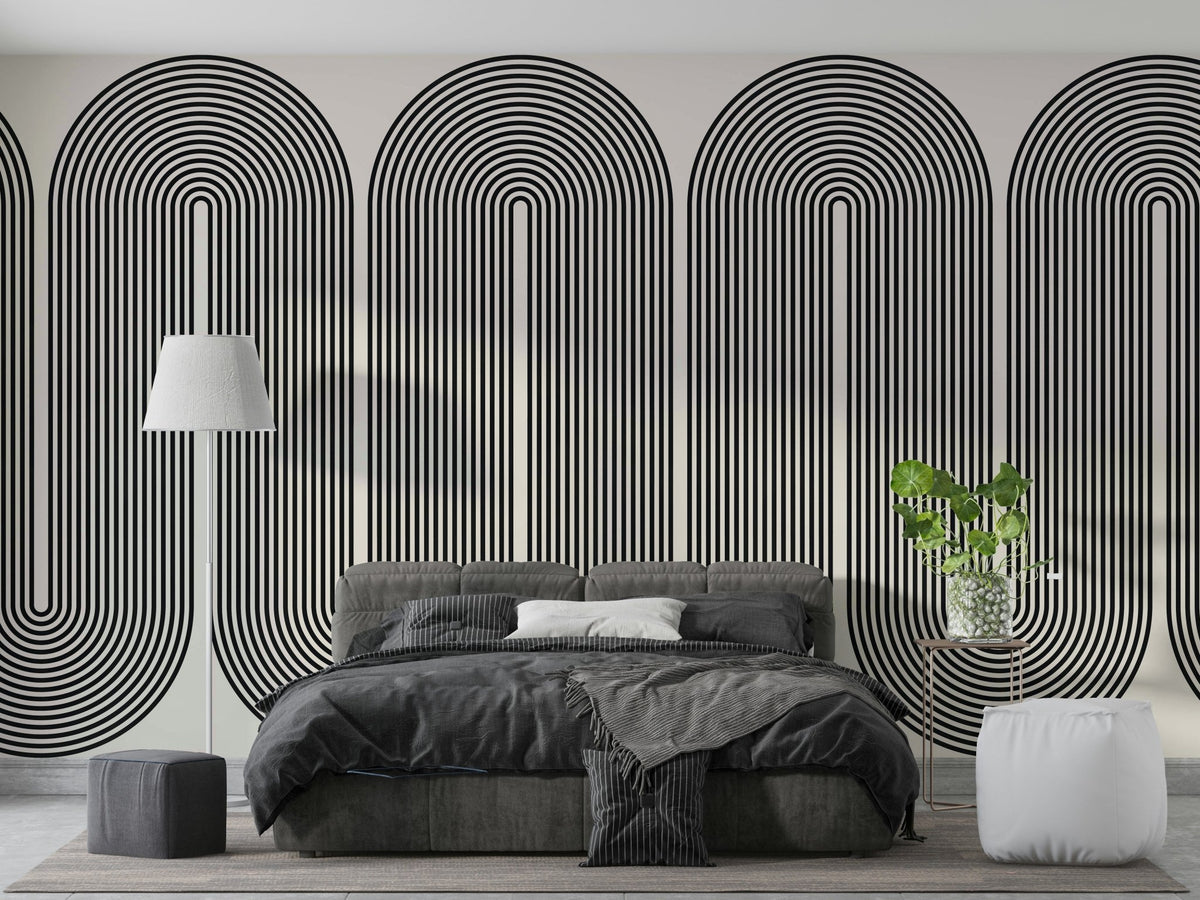 Mod Arc wallpaper mural in black and cream concentric arches behind a gray bed and white floor lamp in a bedroom