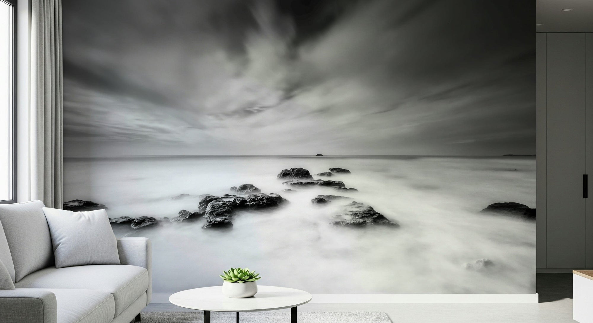 Monochrome Seascape Dream mural of misty sea and rocks behind a white sofa and round side table in a living room