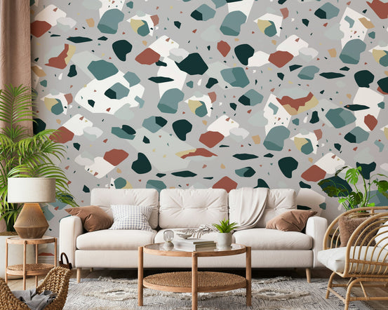 Fragment Fusion wallpaper mural with teal and terracotta terrazzo shapes on grey behind a cream sofa in a living room