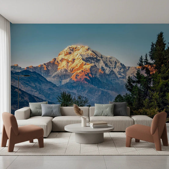 Mountain Dawn wallpaper mural of a golden snow-capped peak at dawn behind a beige sectional and rust armchairs