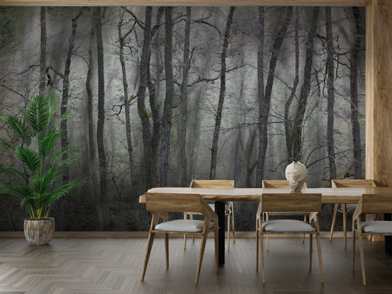 Mysterious Forest Landscape gray trees wall mural in a dining room with a live-edge wood table and palm plant