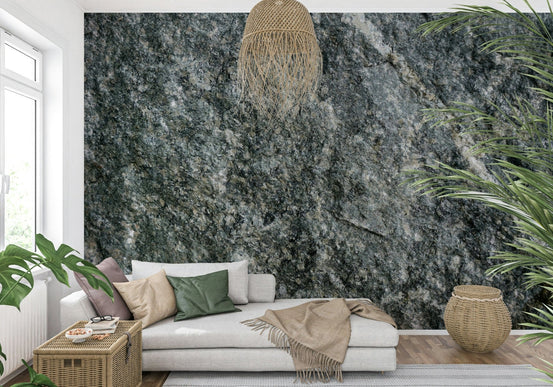 Natural stone finish wallpaper mural in gray-green behind a beige sofa with a rattan pendant in a living room