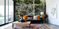 Overgrown stone wall mural in modern living room, soft green foliage tones