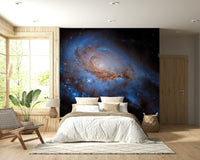 Nebula Dreams wall mural of a blue galaxy behind a white bed and woven chair in a wood-panelled bedroom
