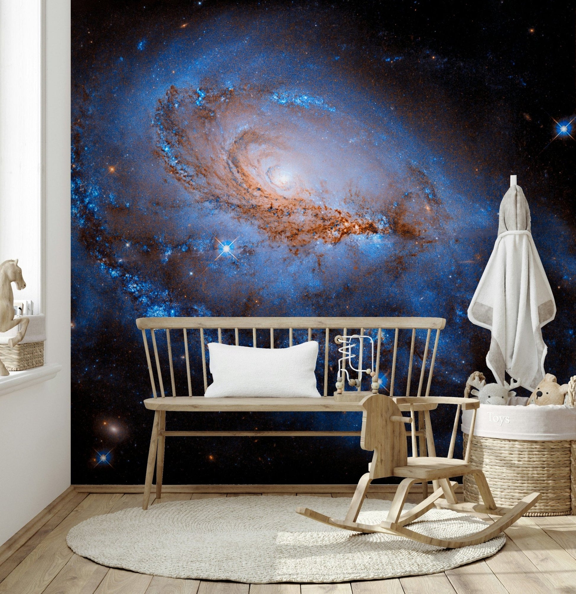 Nebula Dreams wall mural of a blue galaxy on black behind a wood spindle bench and rocking chair in a nursery