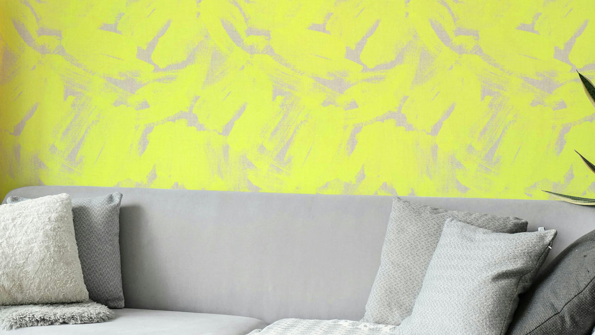 Neon Yellow Abstract Brushstroke wallpaper in bright yellow and gray behind a gray sofa with textured cushions