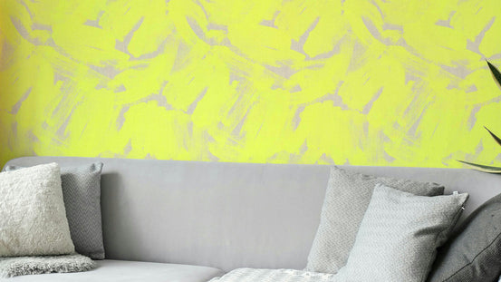 Neon Yellow Abstract Brushstroke wallpaper in bright yellow and gray behind a gray sofa with textured cushions