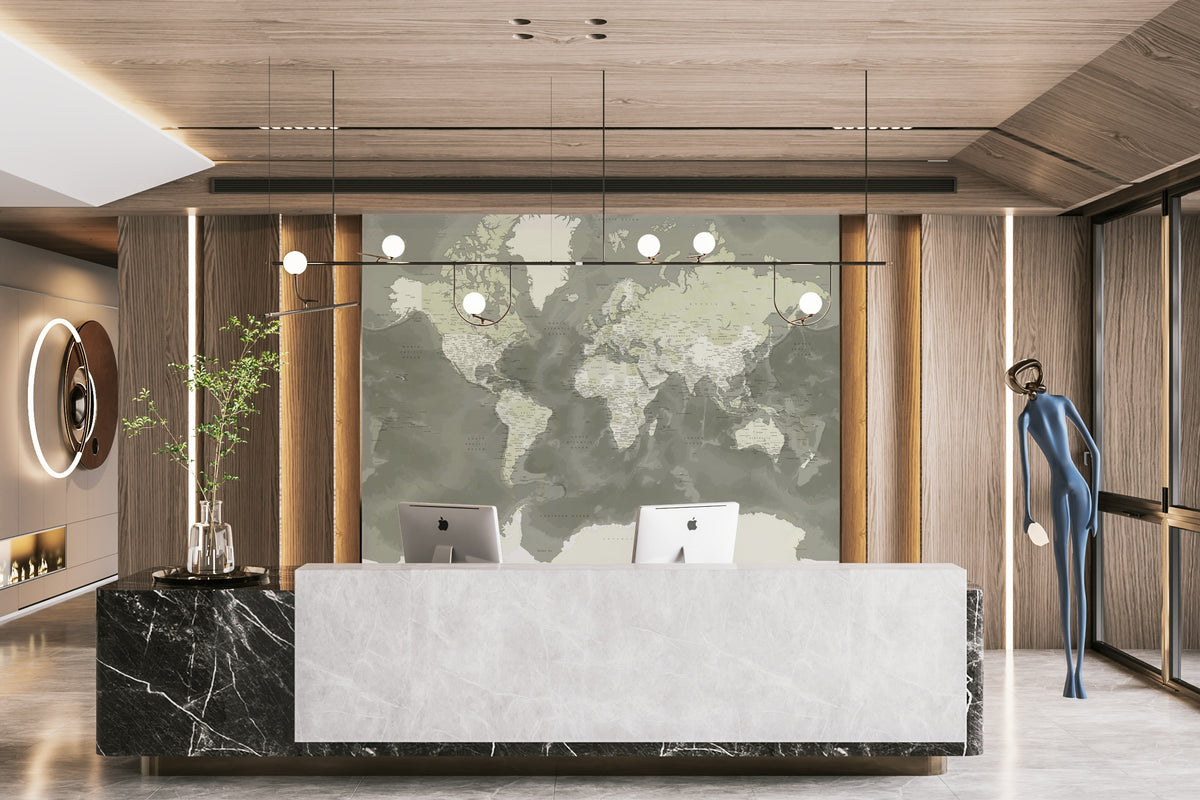 Neutral Green Watercolor World Map wallpaper mural in sage green behind a marble reception desk with two iMacs