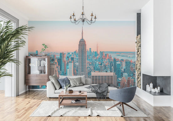 NYC Sunrise Skyline wallpaper mural of Manhattan at dawn behind a white sofa and wood cabinet in a living room