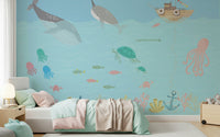 Playful underwater wall mural behind toddler bed, soft blue color palette, nursery feature wall