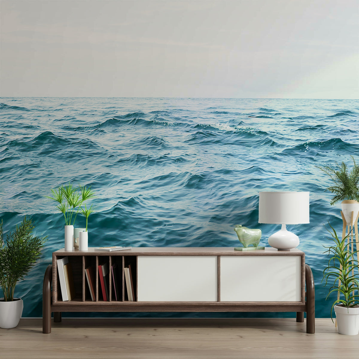Ocean Serenity wallpaper mural of calm blue sea waves behind a wooden media credenza with books and a white lamp