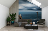 Ocean edge wallpaper in bedroom, soft waves and sand tones above headboard
