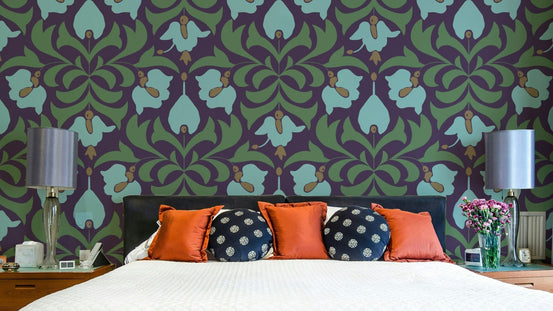 Orbisca - Art Nouveau Flora wallpaper with aubergine and sage tulip damask behind a bed with orange and navy pillows in a bedroom