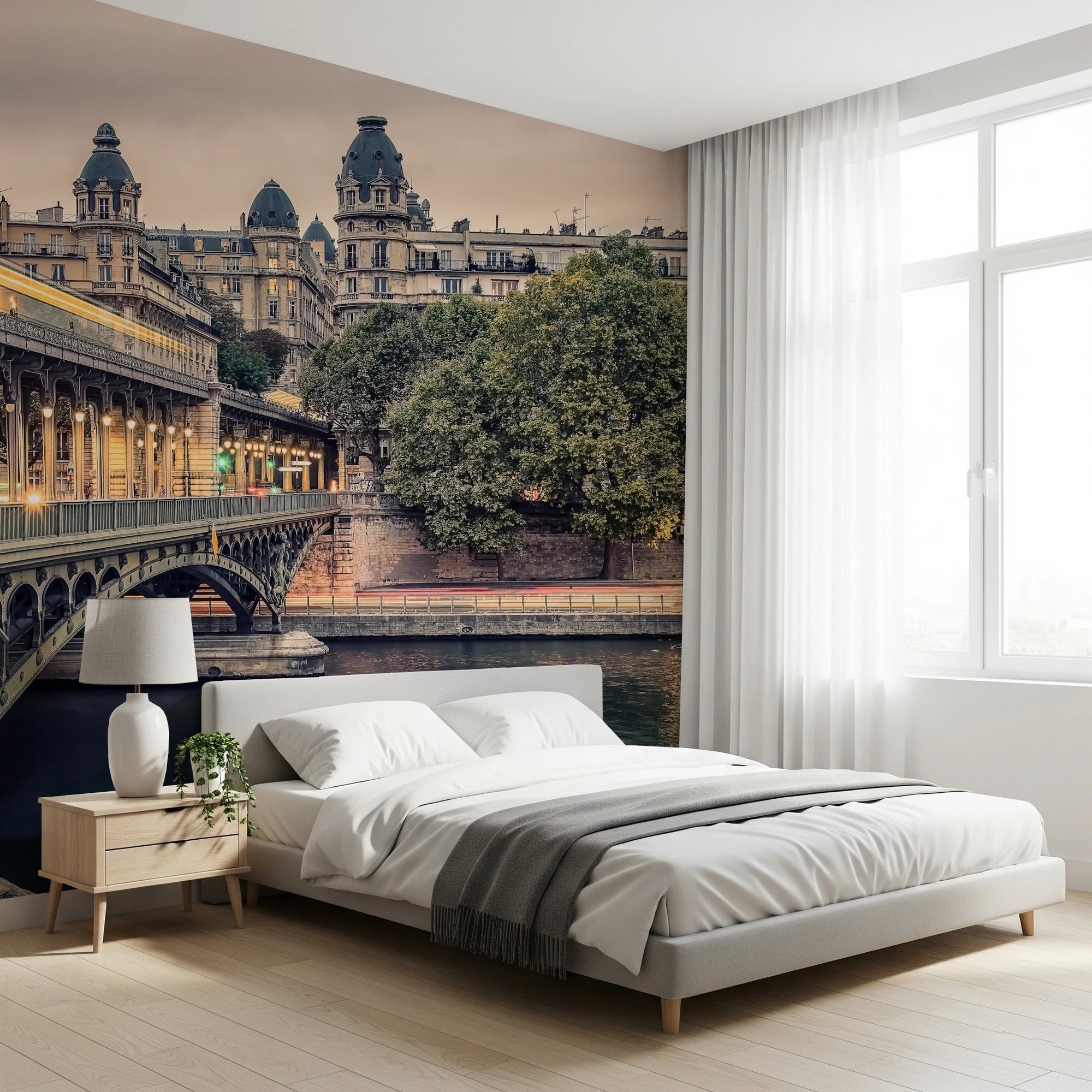 Parisian Bridge Lights wallpaper mural of the lit Bir-Hakeim bridge and Seine beside a white bed and wood nightstand in a bedroom