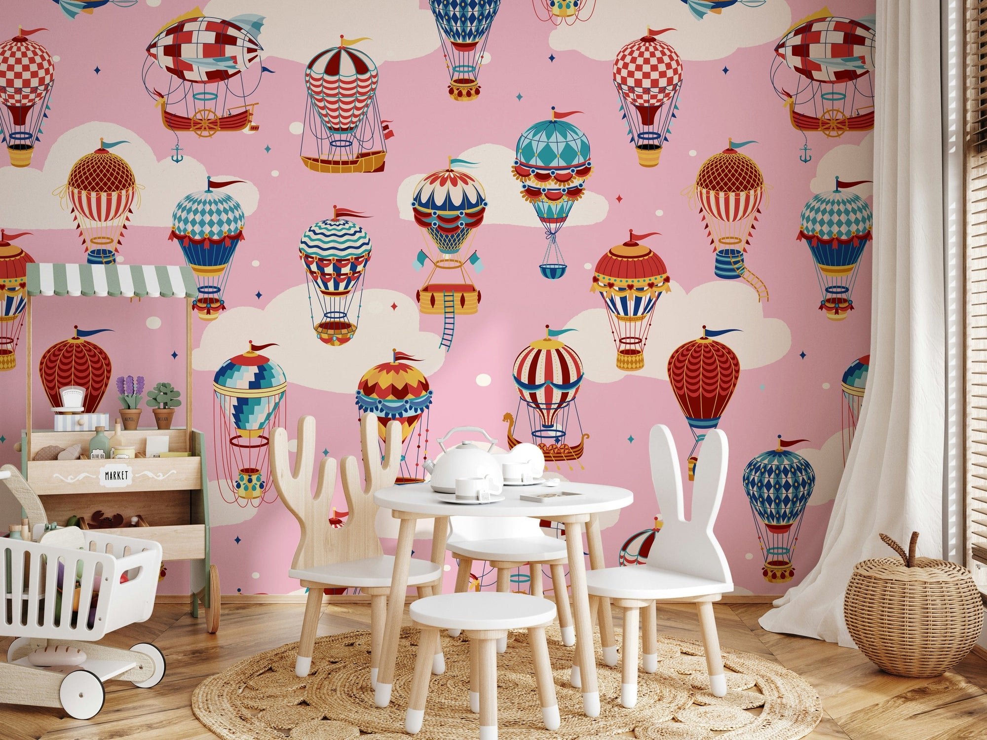 Cloudbound Balloons wallpaper mural of balloons in pink clouds in a playroom with a wood market stall and bunny-ear chairs
