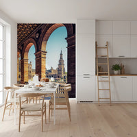 Plaza de España View wallpaper mural of Seville brick arches and tower behind a white dining table in a bright kitchen
