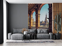 Plaza de España View wallpaper mural of the sunlit plaza arches above a grey sofa by a slatted wall and cactus