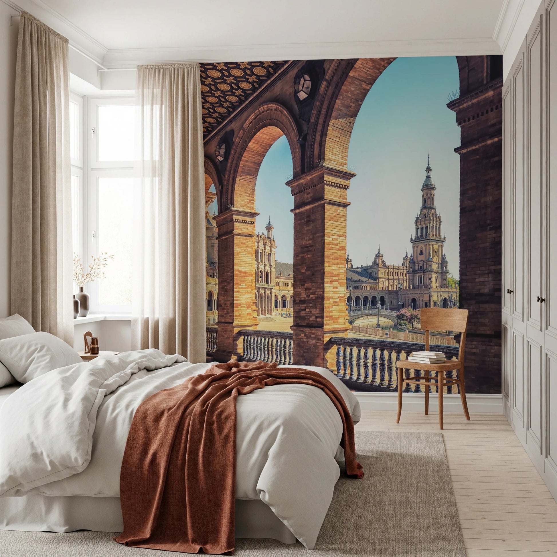 Plaza de España View wallpaper mural of Seville arches and tower behind a white bed with a rust throw in a bedroom