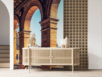 Plaza de España View wallpaper mural of sunlit brick arches beside a woven cane sideboard and grid-panel wall