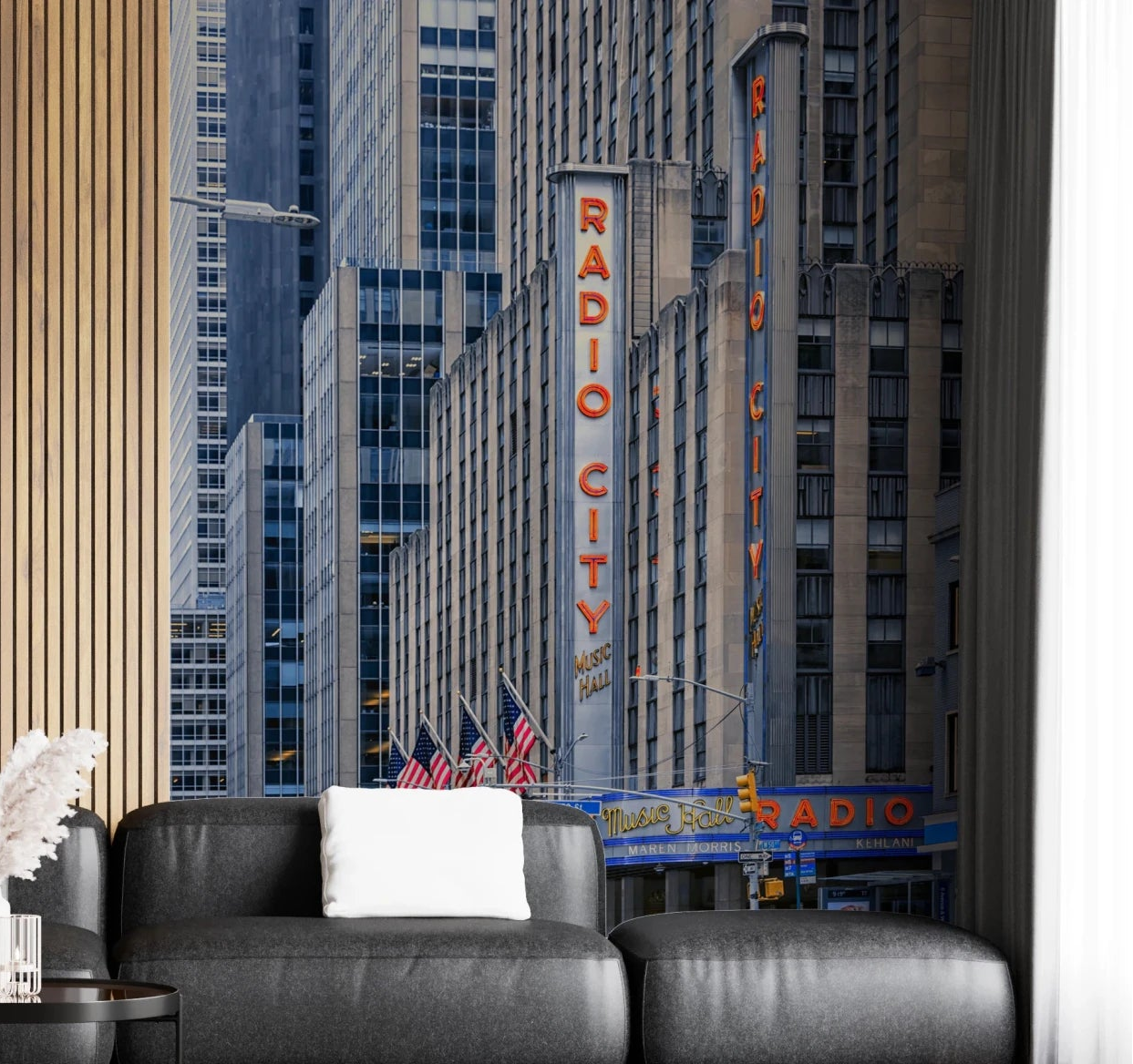 Radio City's Glow wallpaper mural with the red Radio City neon sign and skyscrapers behind a dark grey leather sofa