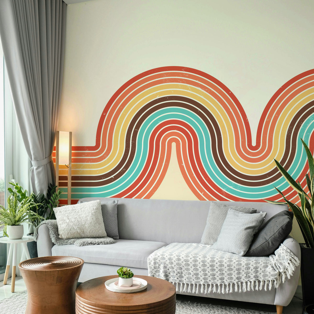 Retro Curvy Lines 3 wallpaper mural in coral and turquoise waves behind a light grey sofa and wood drum tables