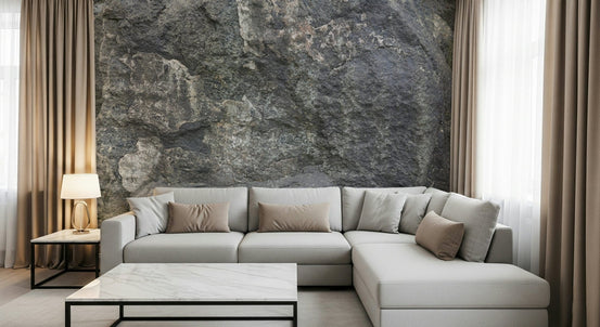 Rocky Surface wallpaper mural in weathered grey stone behind a light grey L-sectional sofa and marble coffee table