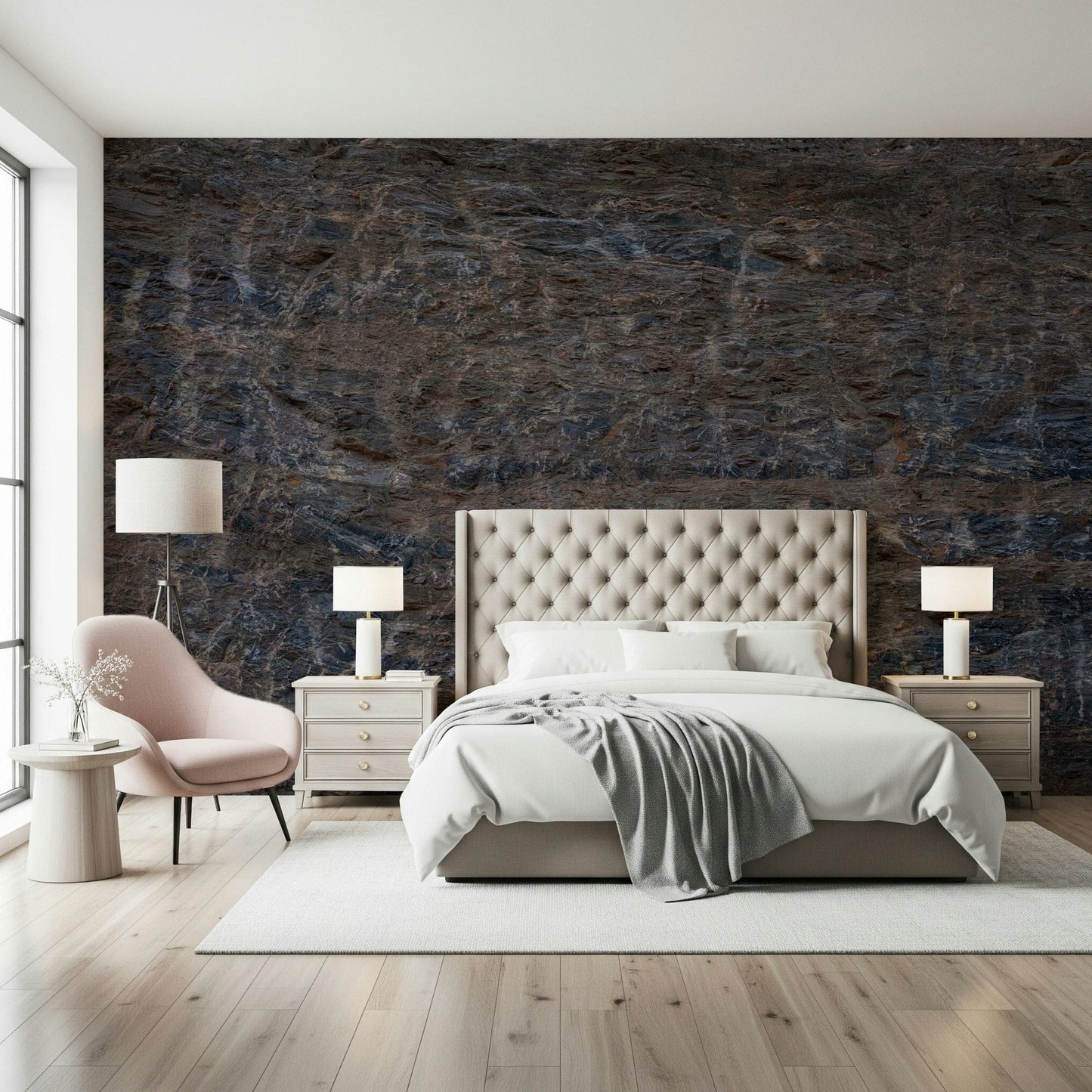 Rocky Terrain wallpaper mural of deep blue-brown stone behind a cream tufted bed and pink armchair in a bedroom