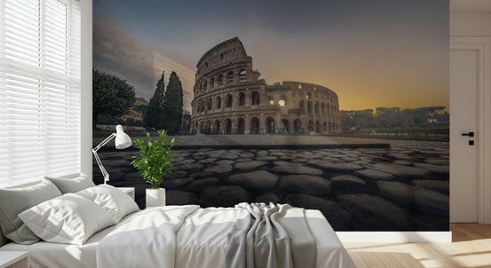 Ancient Rome Sunrise wallpaper mural of the Colosseum at golden sunrise above a white bed and reading lamp in a bedroom