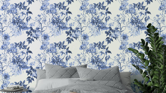 Serene Blue Botanicals wallpaper behind a bed with a grey quilted headboard and pillows in a calm bedroom
