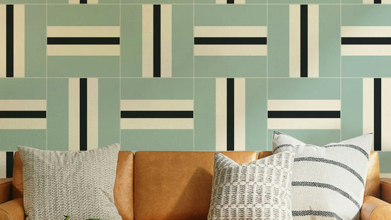 Serene Stripes wallpaper in sage green with black and cream woven tiles above a tan leather sofa