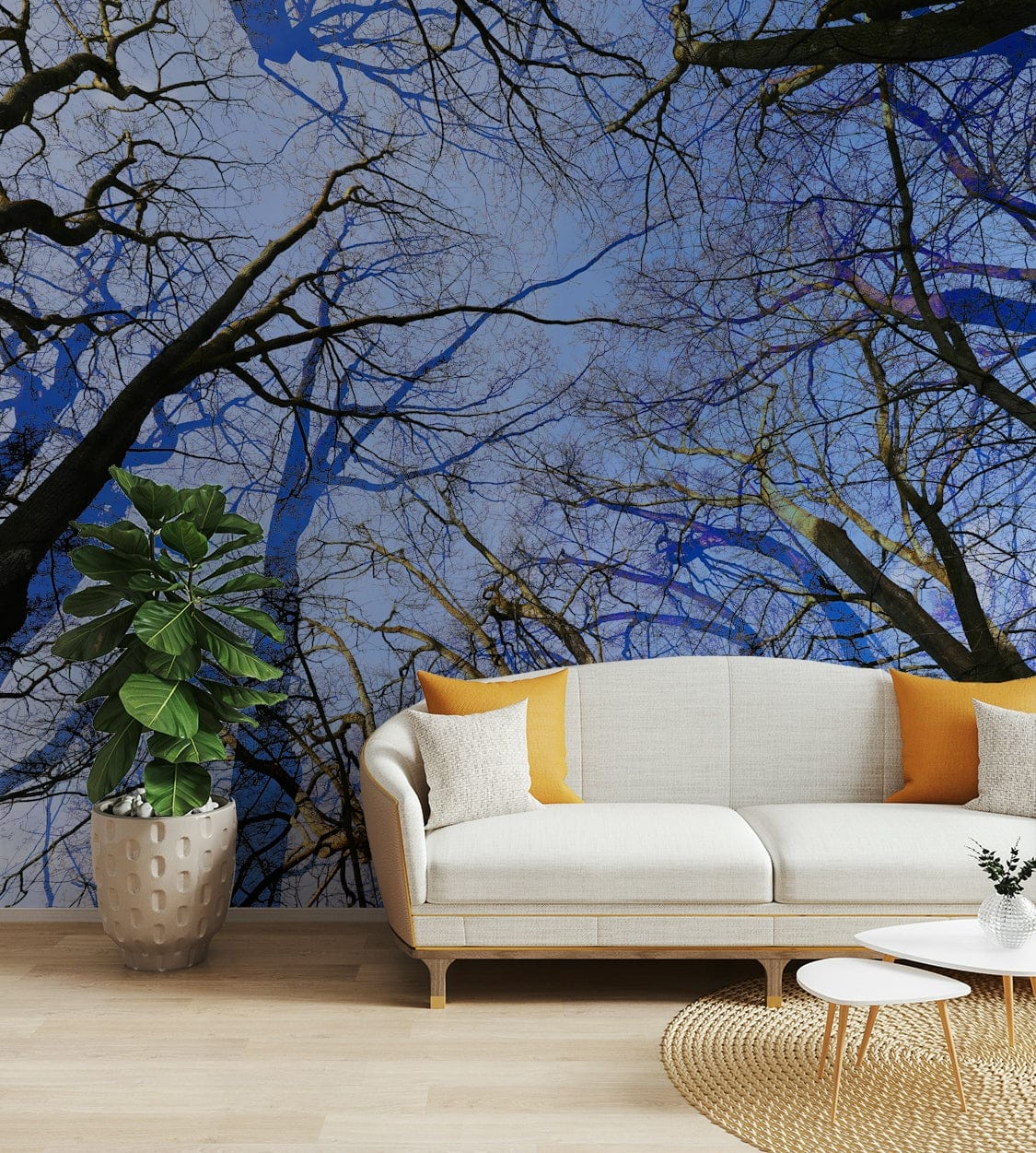 Skyward View Abstract Tree Canopy wall mural of branches on a blue sky behind a cream sofa with orange pillows
