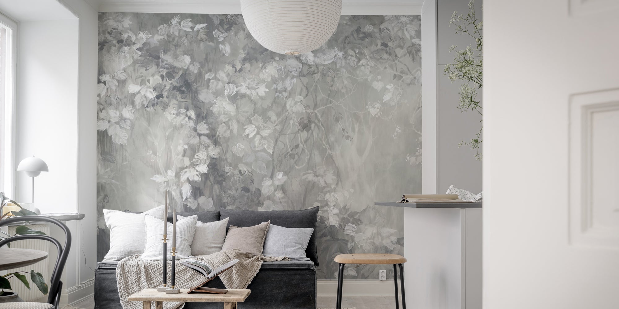 Slate Leaf Silhouette Panorama wallpaper mural in soft gray florals behind a dark sofa in a living room