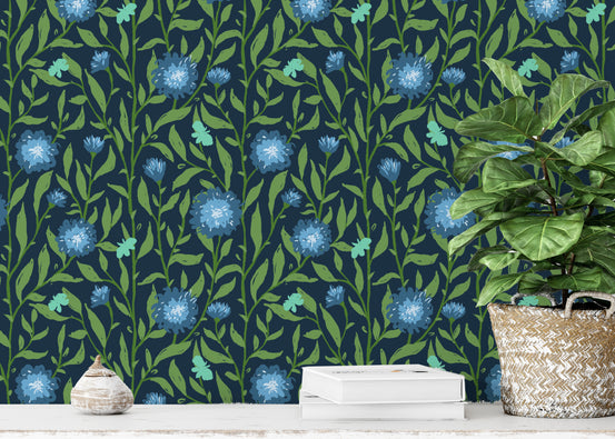 Spring Trellis Dark Green wallpaper mural with blue thistle flowers behind a console, seashell and fiddle-leaf fig in a living room