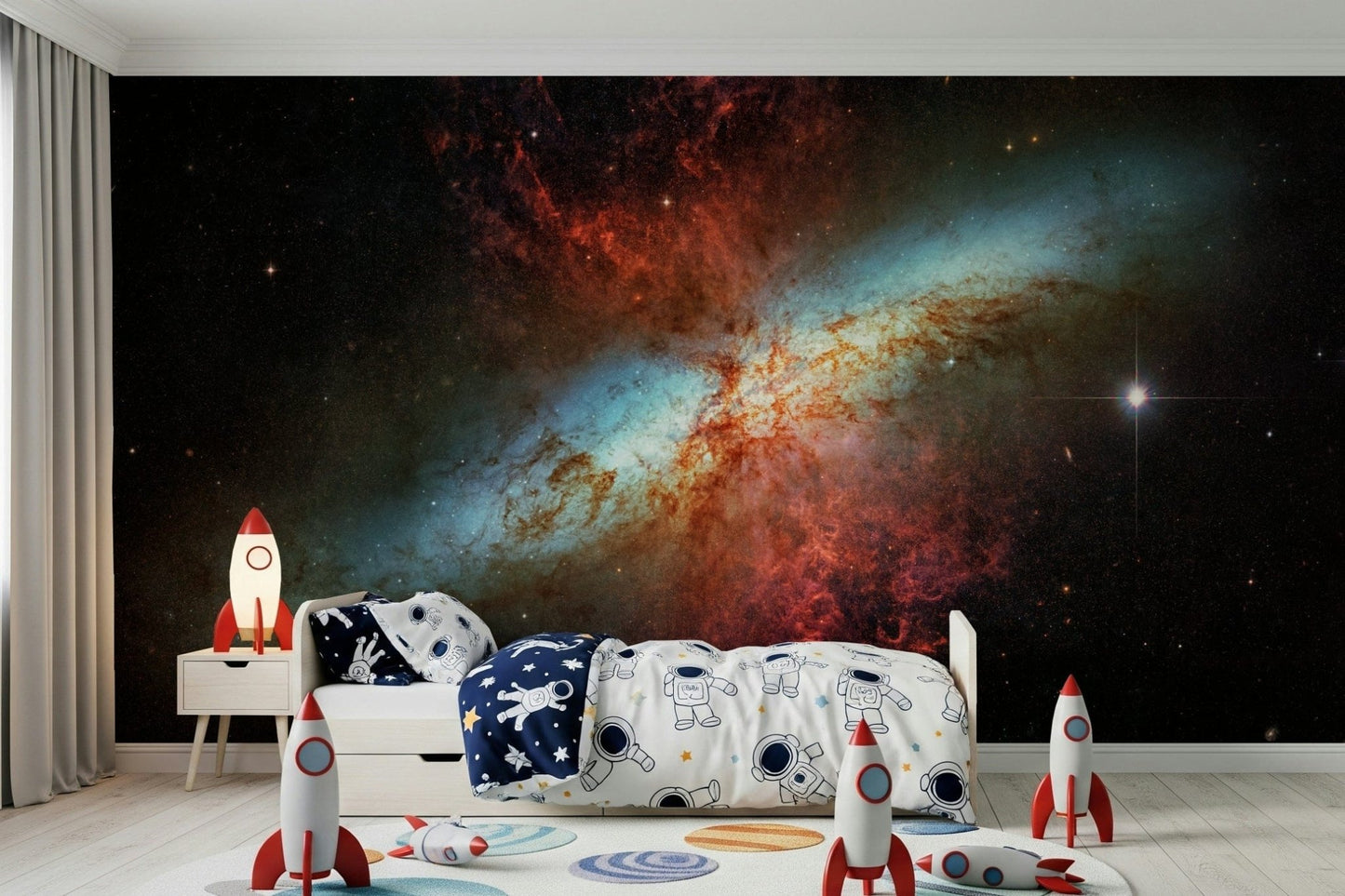 Stardust Symphony wallpaper mural of a red and blue galaxy in a kids room with astronaut bedding and toy rockets