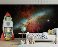 Stardust Symphony wallpaper mural showing a glowing nebula in a kids room with a red rocket bookshelf and globe