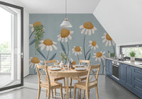 Sunny Daisy Field wallpaper mural of daisies on blue-grey behind a wood dining table in a kitchen with navy cabinets