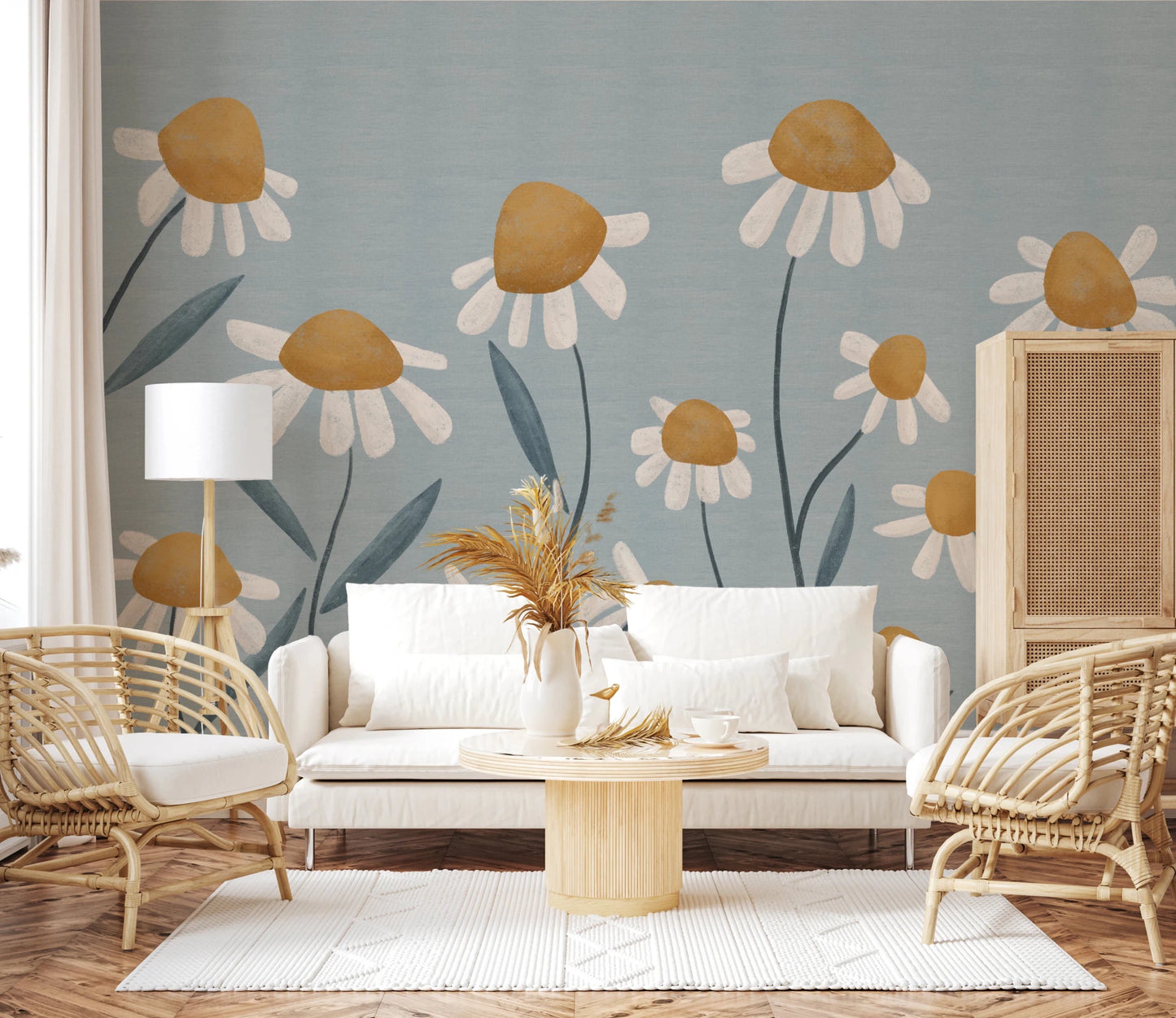 Sunny Daisy Field wallpaper mural of ochre daisies on blue-grey behind a white sofa and rattan chairs in a living room