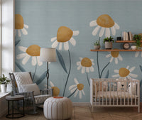 Sunny Daisy Field wallpaper mural with painted daisies on blue-grey behind a grey rocking chair and white crib in a nursery